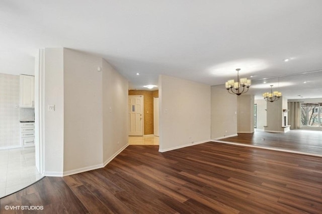 spare room featuring dark hardwood / wood-style flooring and a chandelier