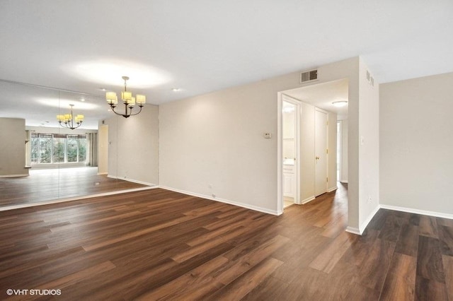 unfurnished room with visible vents, baseboards, a notable chandelier, and wood finished floors