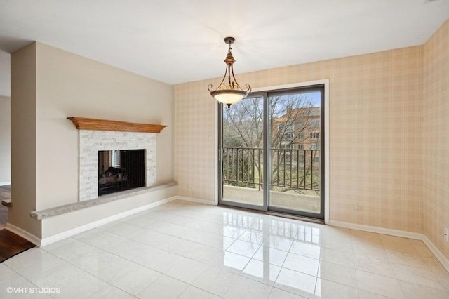 unfurnished living room featuring tile patterned floors, a fireplace with raised hearth, wallpapered walls, and baseboards