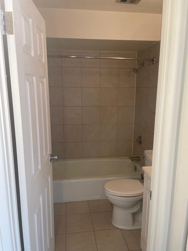 full bathroom with tile patterned flooring, vanity, tiled shower / bath combo, and toilet