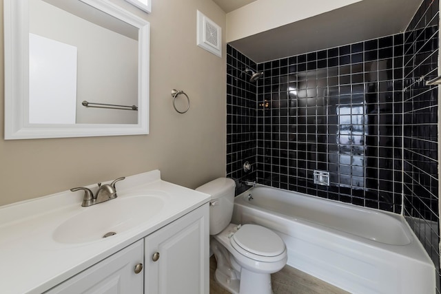 full bathroom with vanity, tiled shower / bath combo, and toilet