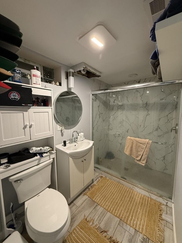 bathroom featuring vanity, a shower with door, and toilet