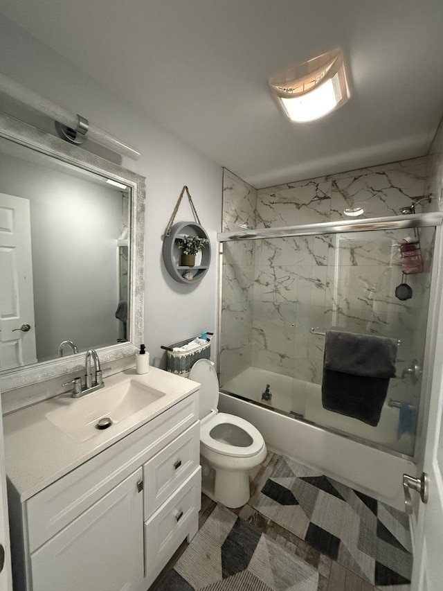 full bathroom featuring toilet, vanity, and shower / bath combination with glass door