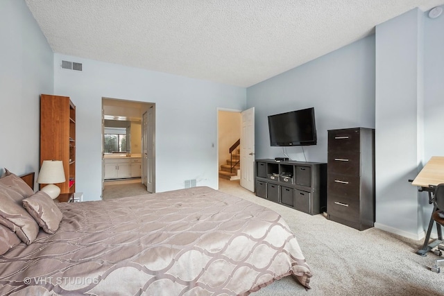 carpeted bedroom featuring ensuite bath and a textured ceiling