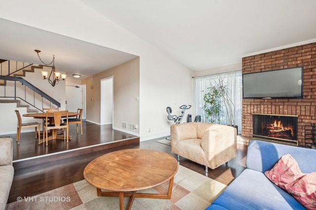 living room featuring lofted ceiling, an inviting chandelier, hardwood / wood-style flooring, and a fireplace