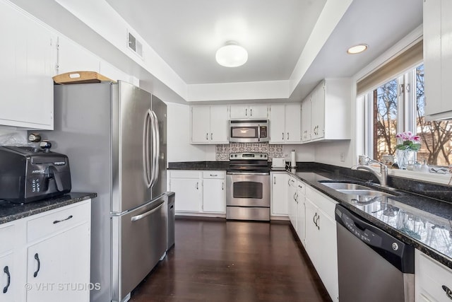 kitchen with sink, backsplash, stainless steel appliances, dark wood-type flooring, and white cabinets