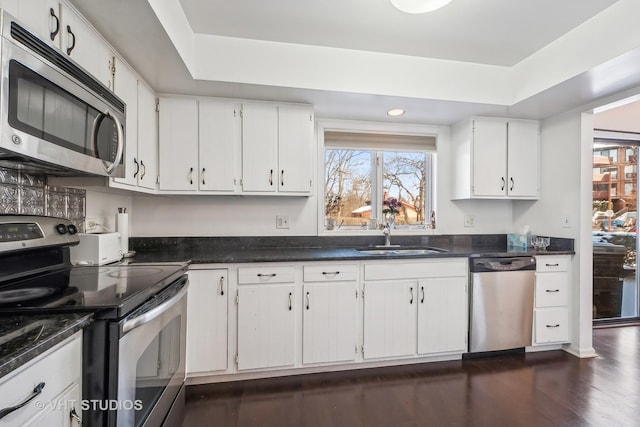 kitchen with appliances with stainless steel finishes, sink, dark hardwood / wood-style flooring, and white cabinets