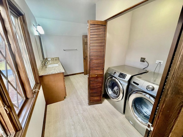 clothes washing area featuring sink, light hardwood / wood-style floors, and washing machine and clothes dryer