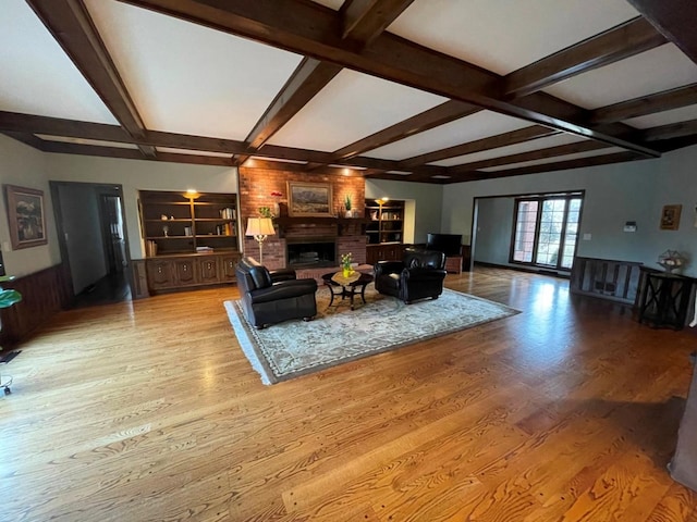 living room featuring a fireplace, beam ceiling, and light wood-type flooring