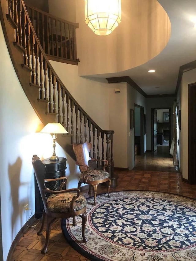 entrance foyer featuring dark parquet flooring, a towering ceiling, and ornamental molding