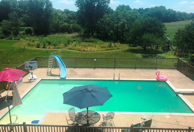 view of swimming pool featuring a yard, a water slide, a diving board, and a patio