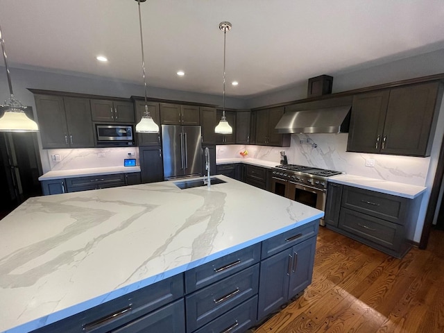 kitchen with a kitchen island with sink, sink, high quality appliances, and wall chimney exhaust hood