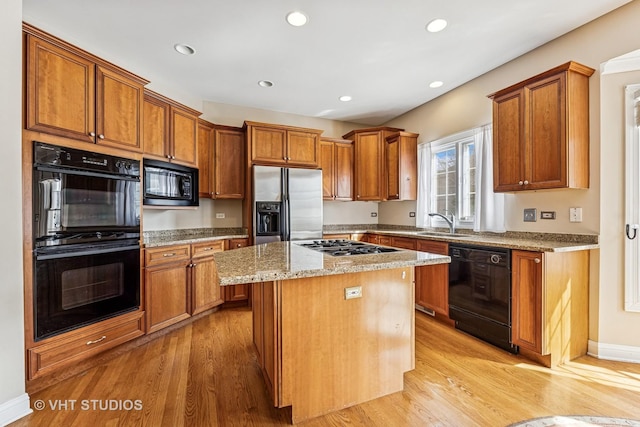 kitchen featuring brown cabinetry, a sink, black appliances, and a kitchen island