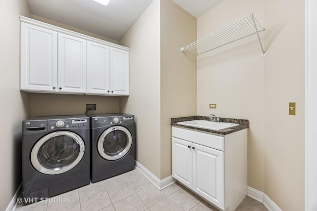 laundry area featuring light tile patterned floors, cabinet space, washing machine and dryer, a sink, and baseboards