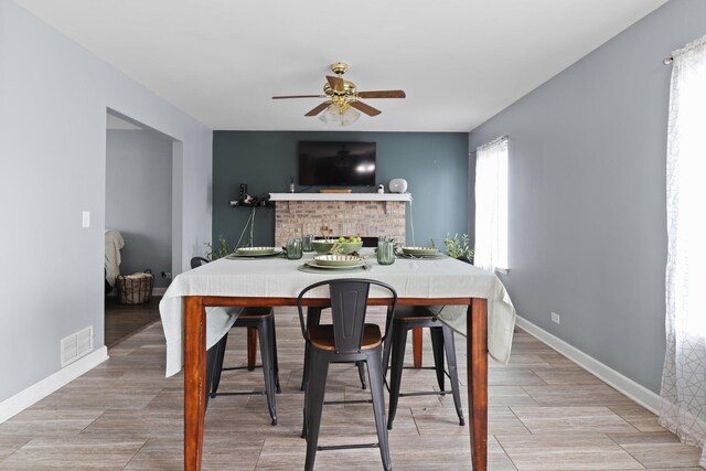 1711 Fallbrook Dr, Hampshire, IL 60140 - dining area with a ceiling fan, a brick fireplace, baseboards, and light wood-style floors