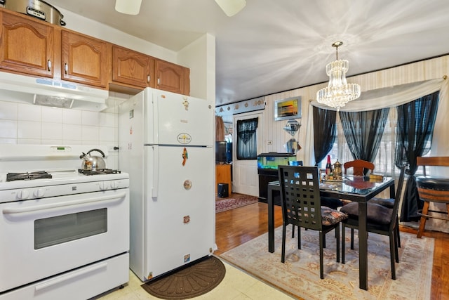 kitchen with backsplash, a notable chandelier, white appliances, and decorative light fixtures