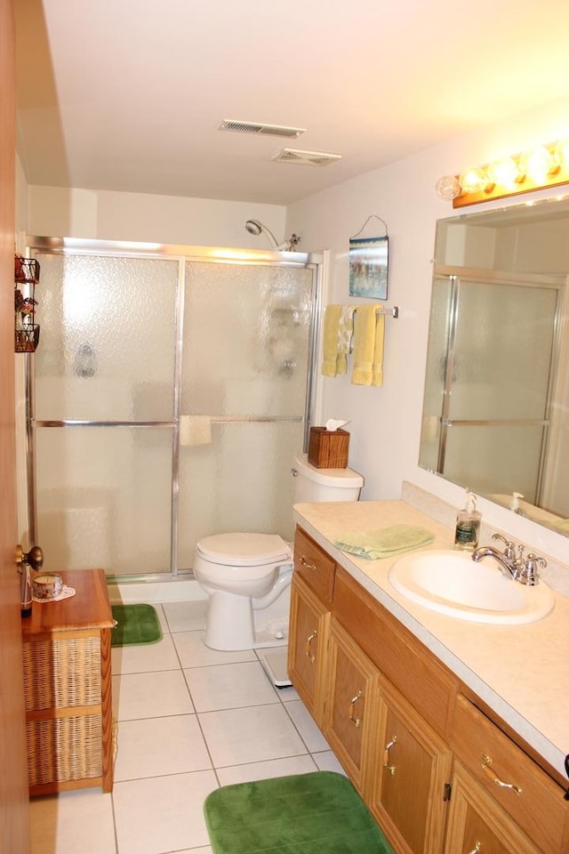 bathroom featuring tile patterned flooring, vanity, a shower with door, and toilet