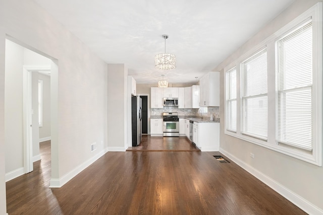 unfurnished living room featuring sink, a notable chandelier, and dark wood-type flooring