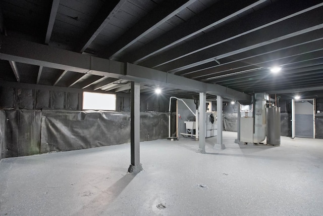 basement featuring water heater, washer / dryer, and heating unit