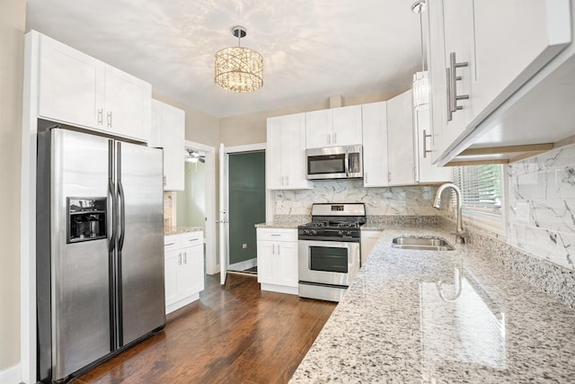 kitchen with hanging light fixtures, white cabinetry, appliances with stainless steel finishes, and sink