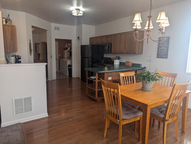 dining room with a notable chandelier, sink, dark wood-type flooring, and independent washer and dryer