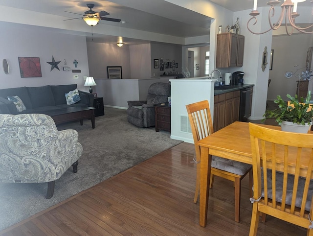 dining space with ceiling fan with notable chandelier, sink, and hardwood / wood-style floors