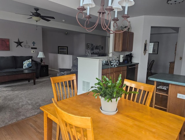 dining area featuring light colored carpet and ceiling fan with notable chandelier