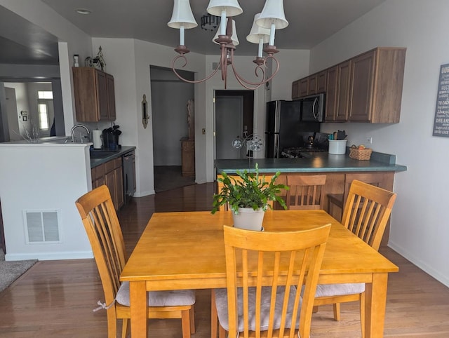 dining area with sink, dark wood-type flooring, and a chandelier