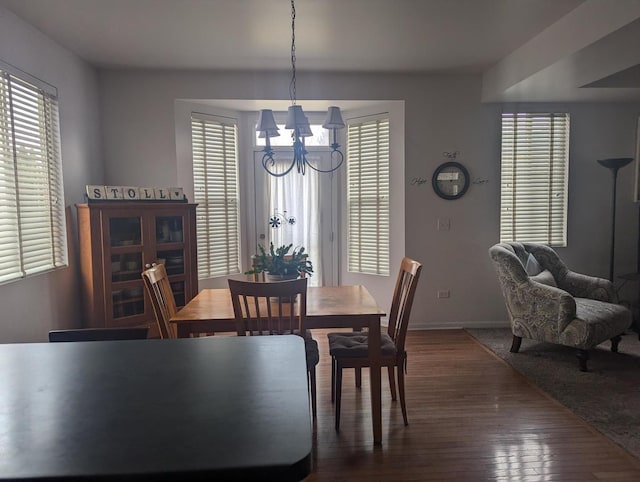 dining space with an inviting chandelier, a healthy amount of sunlight, and dark wood-type flooring