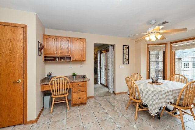 tiled dining room featuring built in desk and ceiling fan