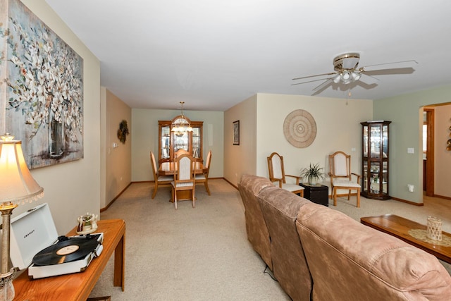 living room featuring ceiling fan with notable chandelier and light colored carpet