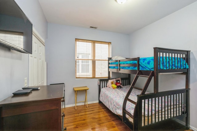 bedroom with visible vents, baseboards, and wood finished floors