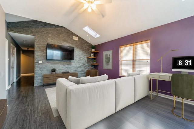 living room featuring lofted ceiling with skylight, an accent wall, visible vents, and wood finished floors