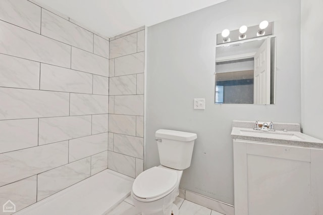 bathroom with vanity, a tile shower, and toilet