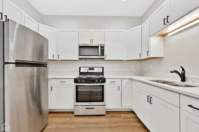 kitchen featuring appliances with stainless steel finishes, light hardwood / wood-style floors, sink, and white cabinets