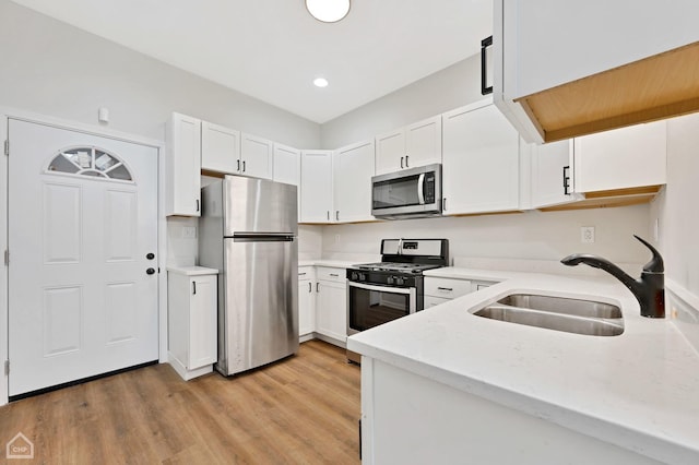 kitchen featuring appliances with stainless steel finishes, light hardwood / wood-style floors, sink, and white cabinets