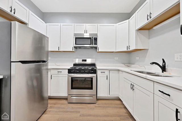 kitchen featuring stainless steel appliances, white cabinetry, sink, and light hardwood / wood-style floors