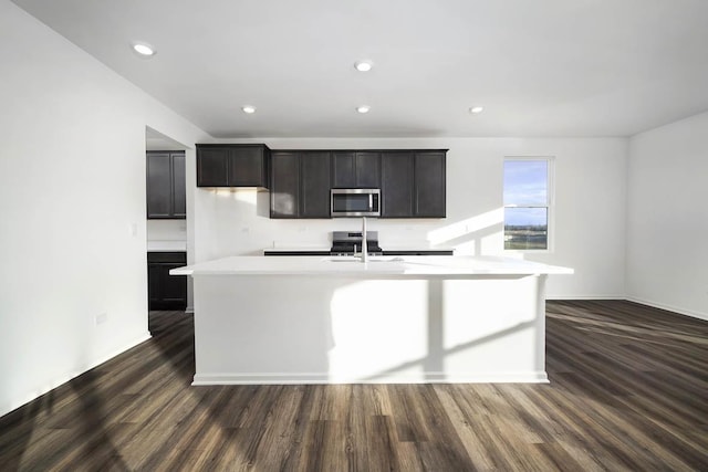 kitchen with sink, dark wood-type flooring, and a center island with sink