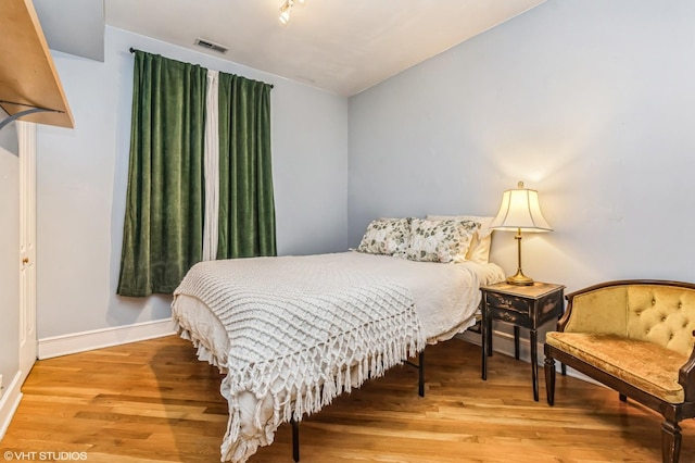 bedroom featuring baseboards, visible vents, and wood finished floors