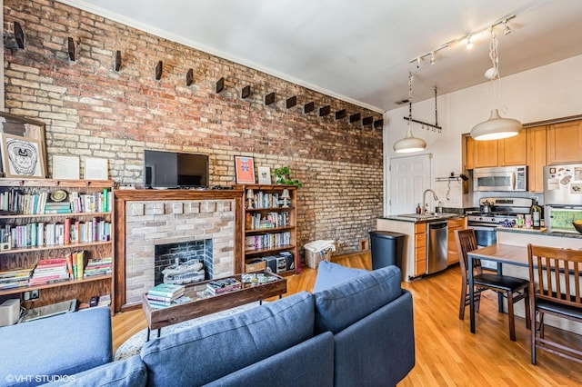 living room featuring a brick fireplace, light wood-style flooring, and brick wall