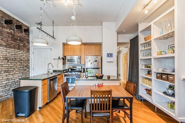 kitchen featuring a peninsula, light wood-style flooring, appliances with stainless steel finishes, and a sink