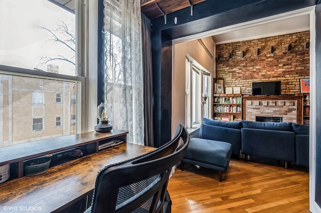 office area featuring brick wall, a fireplace, and wood finished floors