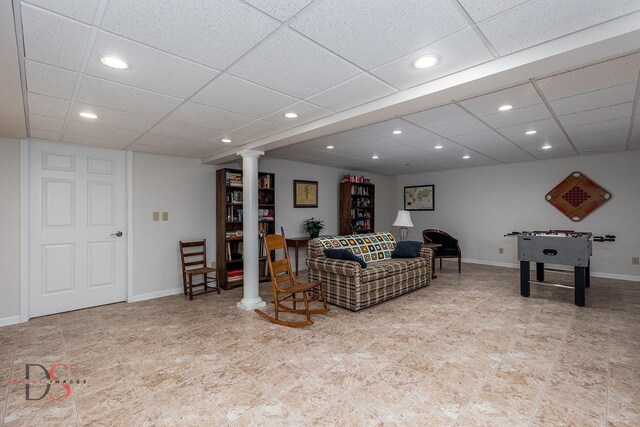 living room with decorative columns and a drop ceiling