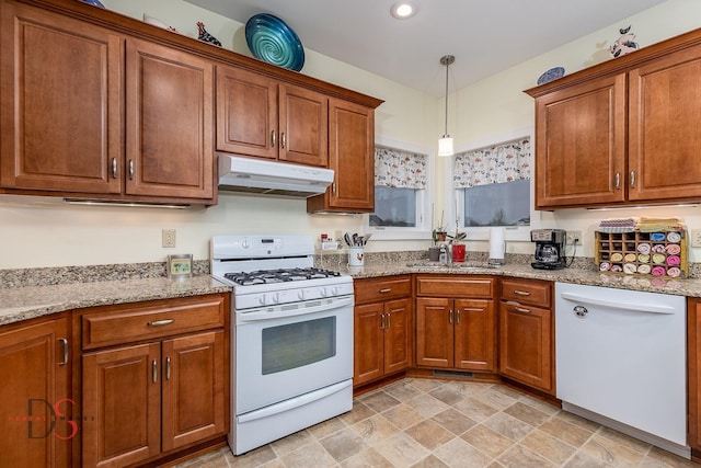 kitchen with light stone countertops, sink, pendant lighting, and white appliances