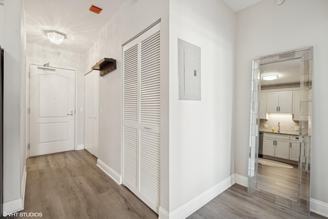 corridor with sink, light hardwood / wood-style flooring, and electric panel