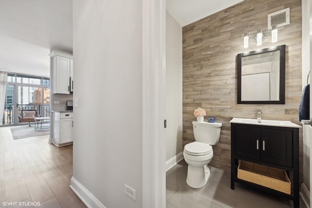 bathroom featuring vanity, toilet, and wood walls