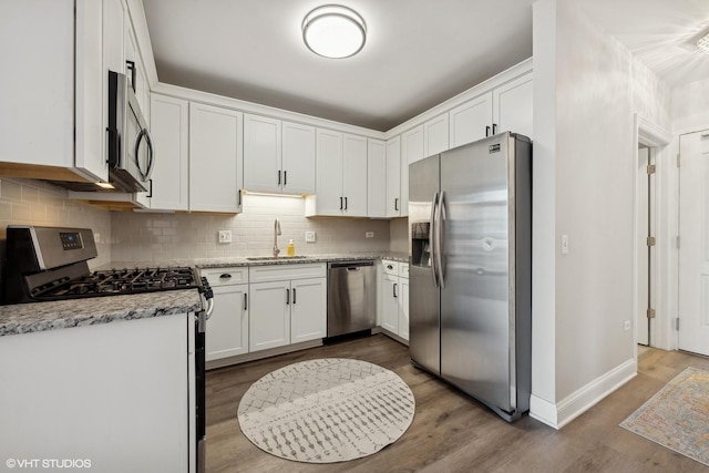 kitchen with tasteful backsplash, sink, white cabinets, stainless steel appliances, and light stone countertops