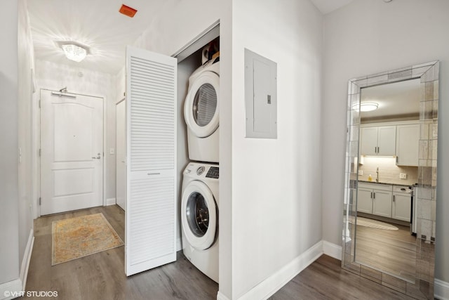 laundry area with stacked washer and dryer, wood-type flooring, and electric panel