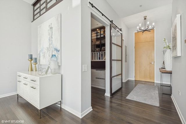 foyer entrance with a chandelier, dark wood-type flooring, and a barn door