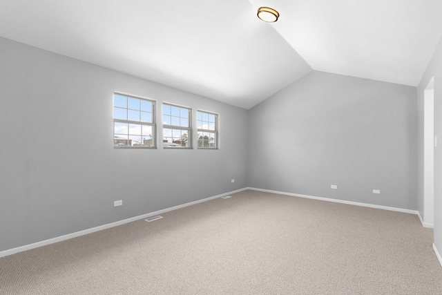 carpeted spare room featuring lofted ceiling